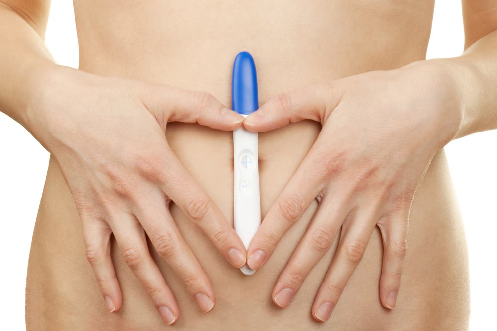 妊娠検査薬と女性のお腹の写真